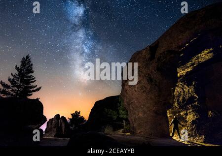 Silhouette eines Mannes in der Nacht, der eine Höhle im Berg mit einer Fackel unter einer erstaunlichen Milchstraße erkundet. Soria, Spanien Stockfoto