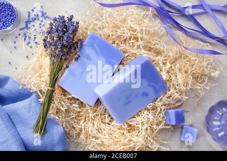 Zwei selbstgemachte Lavendelseifen, Lavendelextraktflasche und trockene Lavendelblüten. Draufsicht. Stockfoto