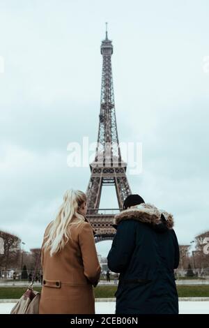Rückansicht des Paares, das am Eiffelturm in bewölktem Tag in Paris, Frankreich steht. Stockfoto