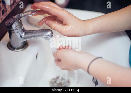 Kind schließt den Wasserhahn mit fließendem Wasser. Wasser sparen. Händewaschen zum Schutz vor dem Coronavirus. Stockfoto