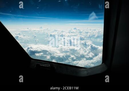 Luftaufnahme von Flugzeugfenstern zum endlosen blauen Himmel mit Dichte weiße Wolken Stockfoto