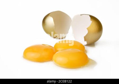 Zerbrochenes goldenes Ei und drei Eigelb Stockfoto
