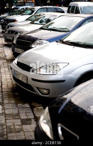 Perspektivische Ansicht der geparkten Autos in Reihe am Straßenrand von Stadtstraße bei Tageslicht Stockfoto