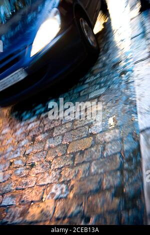 Verschwommene Autos mit glühenden Lichtern in Bewegung fahren auf Asphalt Stadtstraße in der Dämmerung Stockfoto