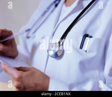 Crop-Ansicht des Mannes in weißer Arzt Uniform mit Stethoskop Schreiben auf ein Stück Papier mit Stift Stockfoto