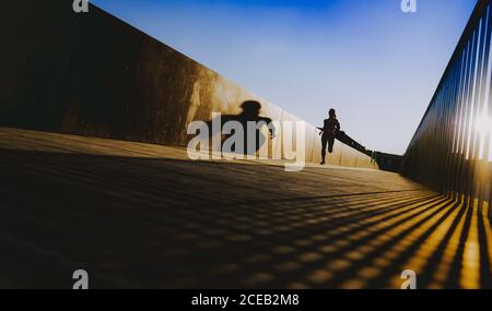 Junge Dame in Sportkleidung auf Wanderweg in sonniges Wetter mit blauem Himmel läuft Stockfoto