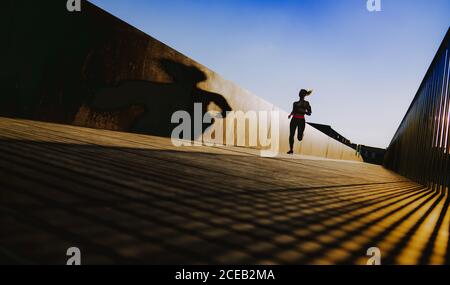 Junge Dame in Sportkleidung auf Wanderweg in sonniges Wetter mit blauem Himmel läuft Stockfoto