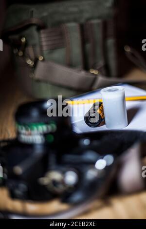 Szene mit Analogkamera, Filmrollen, Notizblock mit Stift und Fototasche auf altem Holztisch. Stockfoto