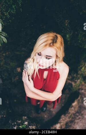 Junge blonde Frau, die vor dem Wasserfall steht Stockfoto