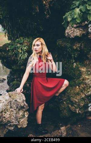 Junge blonde Frau, die vor dem Wasserfall steht Stockfoto