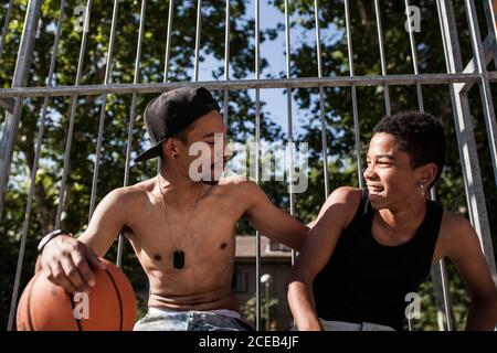 Afro-junge Brüder spielen Basketball auf dem Hof ihrer Nachbarschaft lächelnd und umarmt Stockfoto