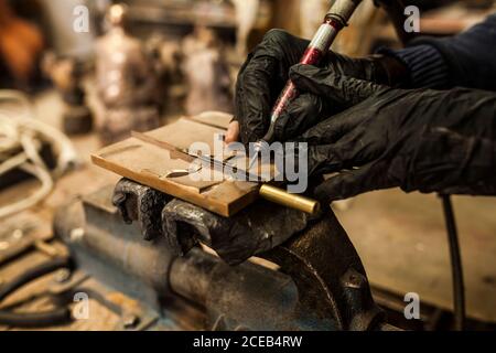Schnittansicht der Hände in schwarzen Gummihandschuhen, die von arbeiten Ausrüstung über Details über Tischlermaschine Werkzeug Stockfoto