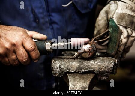Nahaufnahme der Hände des Schmieds, die Eisenball auf der Hand behandeln Amboss Stockfoto
