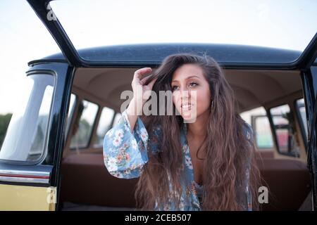 Schöne und junge Frau genießt die Reise in ihrem Vintage-Van mit einigen Freunden Stockfoto