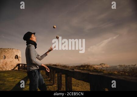 Elegante Dame in Gap Jonglierbälle auf Gras in der Nähe der Küste von Meer und Himmel mit Sonne Stockfoto