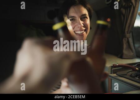 Junge brunette Froehlich pauke Flaschen mit menschlicher Nähe Elektroherd in Mobile home Stockfoto