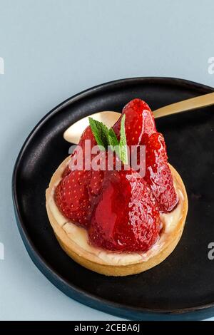 Nahaufnahme von köstlichen Dessert gefüllt mit Sahne und glasierte glänzende Erdbeere auf rosa Hintergrund. Stockfoto