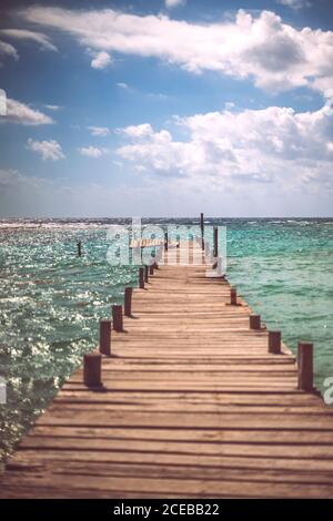 Majestätischer Blick auf dicke Wolken, die über dem sauberen Karibischen Meer schweben Und kleiner Pier mit Boot Stockfoto