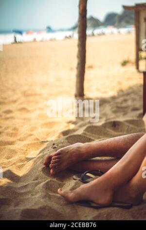 Crop Beine des jungen Paares liegen auf Sand während der Ruhe An einem schönen Strand Stockfoto