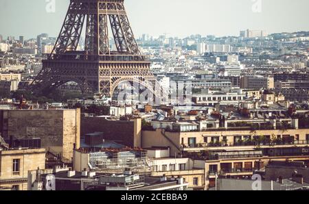 Keller des Eiffelturms, der zwischen Gebäuden auf dem Hintergrund steht Stadtbild in Paris Stockfoto