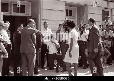 Vivian Malone, eine der ersten Afroamerikaner, die an der Universität von Alabama teilnahmen, geht durch eine Menschenmenge, die Fotografen, Mitglieder der Nationalgarde und den stellvertretenden US-Generalstaatsanwalt Nicholas Katzenbach umfasst, um das Foster Auditorium zu betreten, um sich für den Unterricht am 11. Juni 1963 anzumelden. Stockfoto