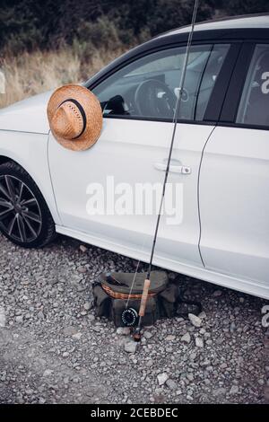 Eine Reihe von Angelsachen befindet sich in der Nähe des modernen weißen Autos Wunderschöne Landschaft Stockfoto