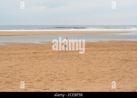 Alter Mann, der auf dem Sand läuft Stockfoto