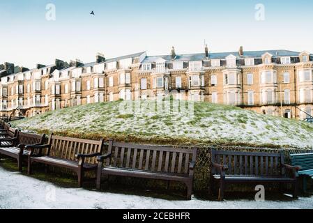 Reihe von Bänken und Raureif grüne Rasen an traditionelle Häuser in Yorkshire, England Stockfoto