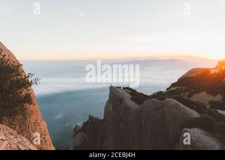 Anonyme Person auf Klippe bei Sonnenaufgang Stockfoto