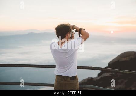 Anonymer Mann, der während des Sonnenaufgangs Fotos vom Meer gemacht hat Stockfoto