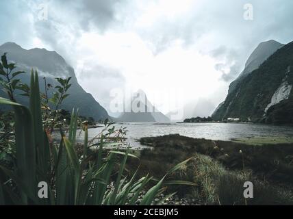 Dicke Wolken schweben über erstaunliche Berge und ruhiges Wasser Herrlicher Tag im Fiordland National Park in Neuseeland Stockfoto