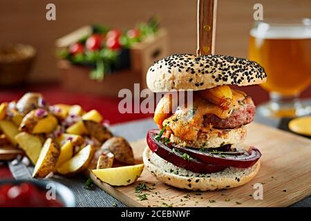 Köstliche Gourmet Burger mit Patty, Zwiebel und Käse serviert mit Kartoffelecken Stockfoto