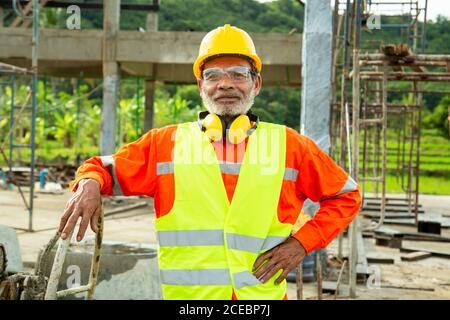 Asian Senior Worker Engineer trägt Helm und Sicherheitskleidung in der Hausbaustelle. Konzept der arbeitenden älteren Menschen Stockfoto