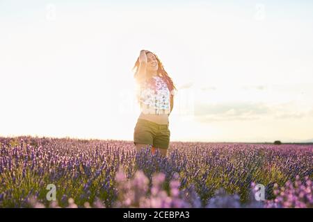 Frau, die bei Sonnenuntergang zwischen dem großen violetten Lavendelfeld steht Stockfoto