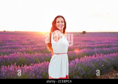 Seitenansicht glücklich attraktive Dame mit Blume in Stretching Hand Zwischen schönen lila Blüten auf Lavendel Feld Stockfoto