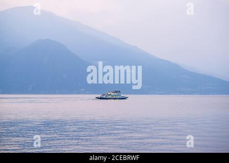 Sonnenuntergang und Abenddämmerung am Comer See. Italien. Lonely Ferry schwimmt auf ruhiger Wasseroberfläche. Idyllische Aussicht. Stockfoto