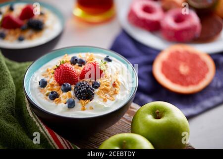 Nahaufnahme der Schüssel mit frischem Joghurt gefüllt und garniert Mit Beerenmischung und Cornflakes an Bord serviert Stockfoto