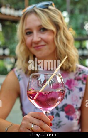 Porträt der reifen Frau sitzt in einem Hinterhof halten Glas Mit Gin und Tonic Stockfoto