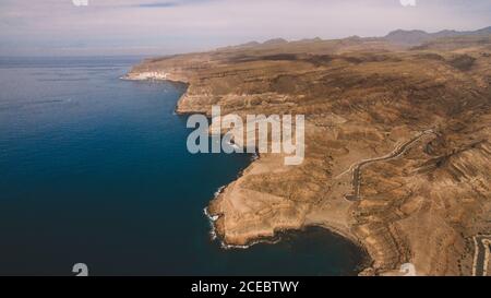 Malerische Luftaufnahme von kargen felsigen Klippen am Ufer von Ruhiges, dunkles Meer an sonnigen Sommertagen auf Gran Canaria Insel Stockfoto
