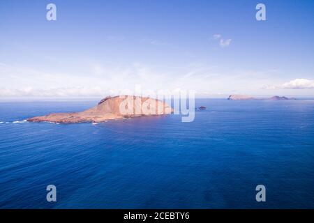 Luftaufnahme des atemberaubenden weiten blauen Meeres mit hohen felsigen Inseln aus der Oberfläche mit klaren erstaunlichen Himmel über an sonnigen Sommertag in La Graciosa, Kanarische Inseln Stockfoto