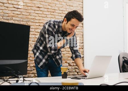 Junger Mann mit Tasse im Gespräch auf dem Smartphone Stockfoto