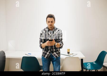 Junger Mann mit Laptop im Gespräch auf dem Smartphone Stockfoto