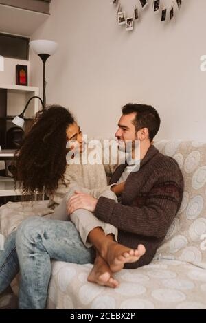 Junge multirassische Paar umarmt auf Sofa Stockfoto