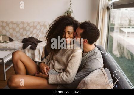 Junge multirassische Paar umarmt auf Sofa Stockfoto