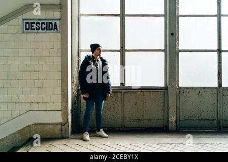 Erwachsener Mann, der am Fenster in der Nähe der Treppe in der Eingangshalle steht. Stockfoto