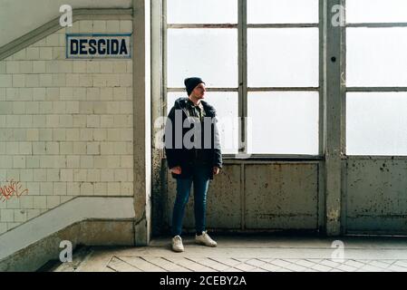 Erwachsener Mann, der am Fenster in der Nähe der Treppe in der Eingangshalle steht. Stockfoto