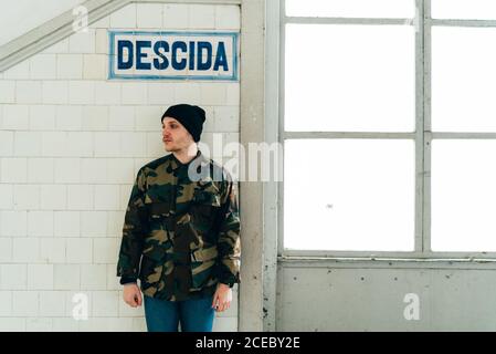 Erwachsener Mann, der am Fenster in der Nähe der Treppe in der Eingangshalle steht. Stockfoto