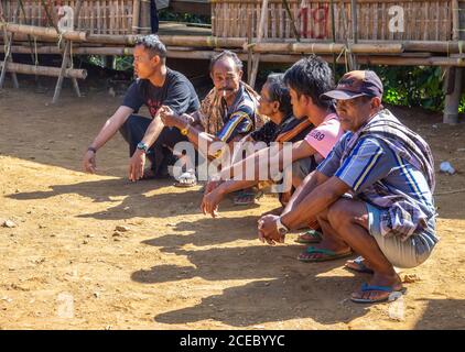 Sulawesi Island, Indonesien - August, 15 2015: Gruppe von ethisch-männlichen Männern in legerer Kleidung, die auf Spukken sitzen und in der Nähe der Baracke an sonnigen Tagen im Dorf miteinander sprechen Stockfoto