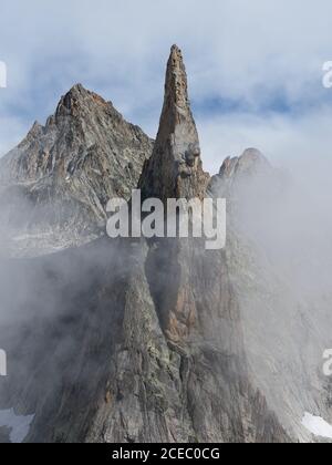 LUFTAUFNAHME. Hoch aufragender Granitgipfel im Nebel. Aiguille de Dibona, Saint-Christophe-en-Oisans, Isère, Auvergne-Rhône-Alpes, Frankreich. Stockfoto