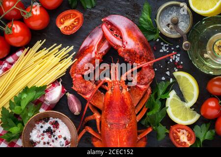 Gedämpfter roter Hummer mit Spaghetti, roten reifen Kirschtomaten, Zitronenkeilen und Petersilie zum Kochen traditionelle italienische Rezept Spaghetti all'astice Stockfoto